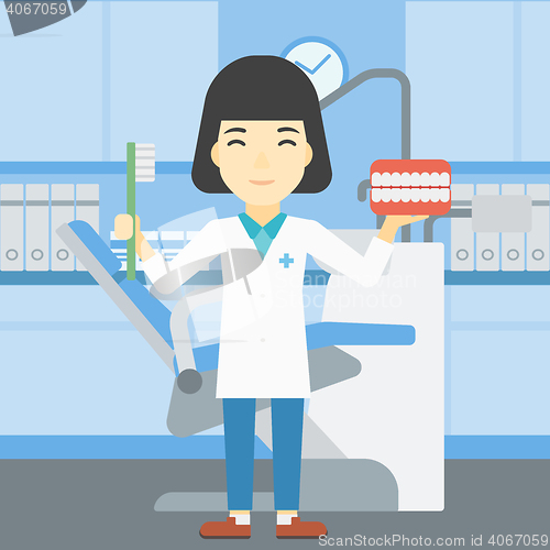Image of Dentist with dental jaw model and toothbrush.