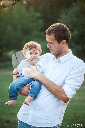 Image of Young beautiful father and little toddler son against green grass