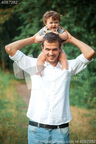 Image of Young beautiful father and little toddler son against green trees