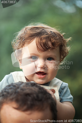 Image of Young beautiful father and little toddler son against green trees