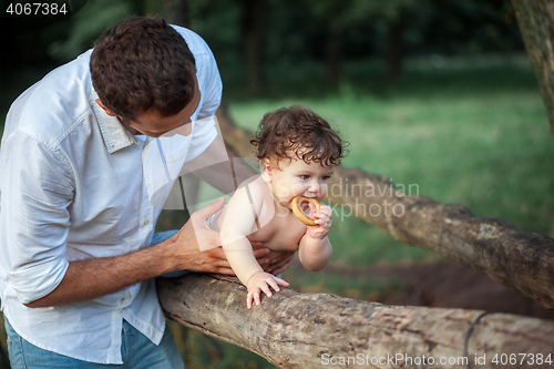 Image of Young beautiful father and little toddler son against green grass