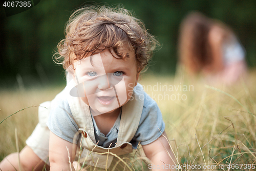 Image of The little baby or year-old child on the grass in sunny summer day.