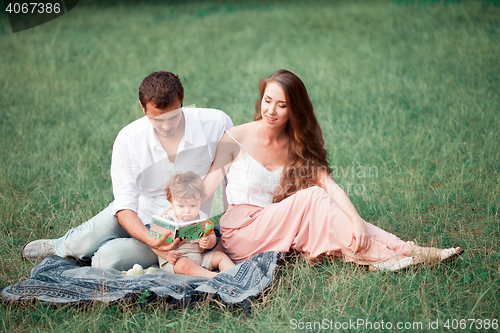 Image of Young beautiful father, mother and little toddler son against green trees