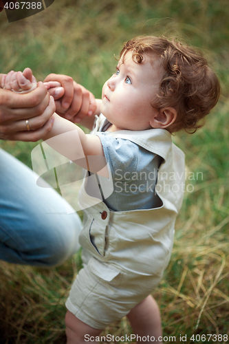 Image of The little baby or year-old child on the grass in sunny summer day.