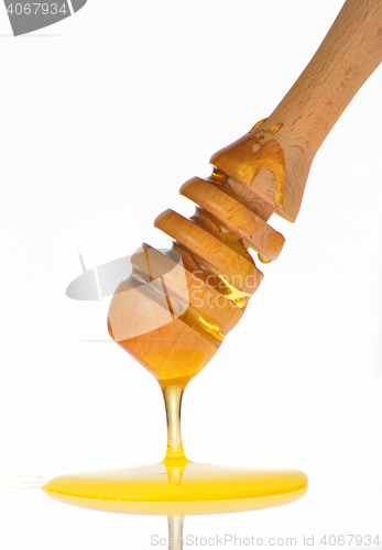 Image of Honey dripping from a wooden honey dipper 