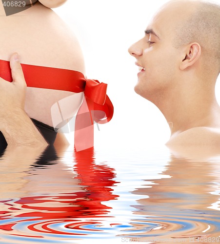 Image of proud father and belly with red ribbon in water