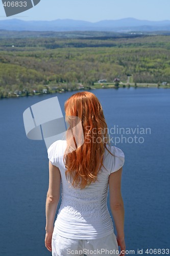 Image of Red-haired girl looking over blue lake