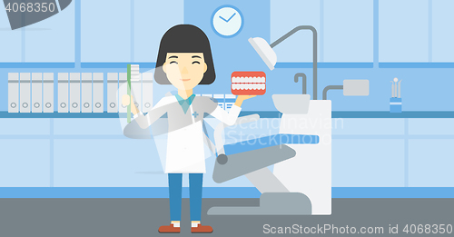 Image of Dentist with dental jaw model and toothbrush.