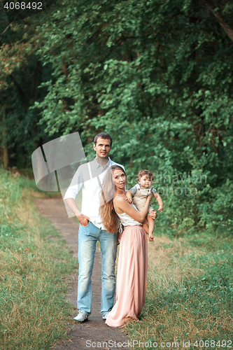 Image of Young beautiful father, mother and little toddler son against green trees