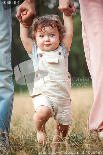 Image of Young beautiful father, mother and little toddler son against green trees