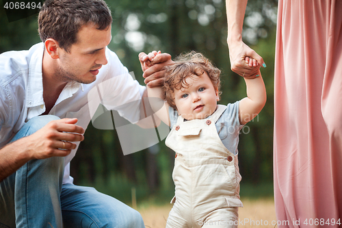 Image of Young beautiful father, mother and little toddler son against green trees