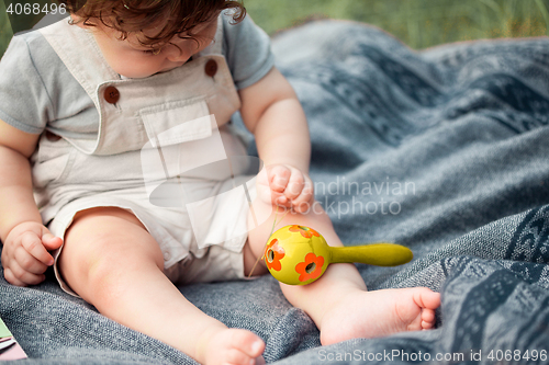 Image of The little baby or year-old child on the grass in sunny summer day.