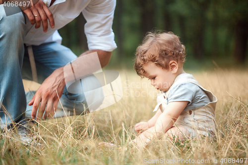 Image of Young beautiful father and little toddler son against green grass