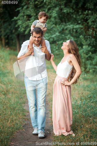 Image of Young beautiful father, mother and little toddler son against green trees