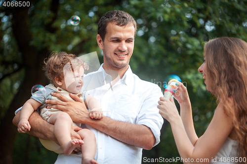 Image of Young beautiful father, mother and little toddler son against green trees