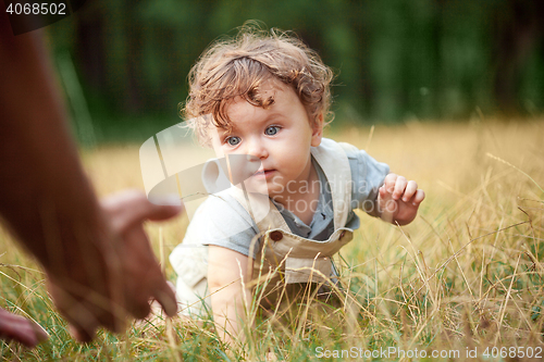Image of The little baby or year-old child on the grass in sunny summer day.