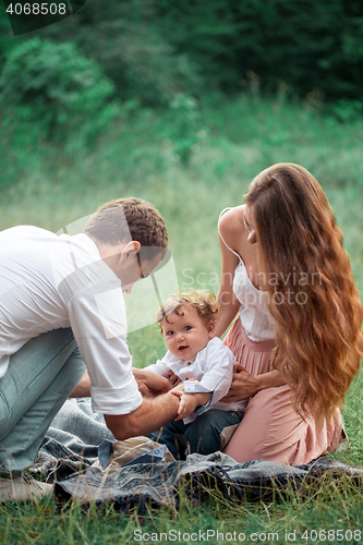 Image of Young beautiful father, mother and little toddler son against green trees