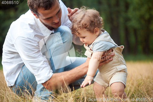 Image of Young beautiful father, mother and little toddler son against green trees