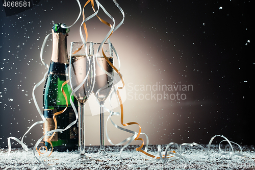 Image of Glasses with sparkling champagne, green bottle and cascading ribbons