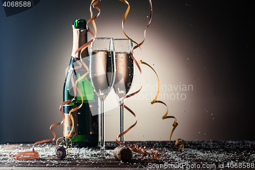 Image of Two glasses with white champagne and green open bottle