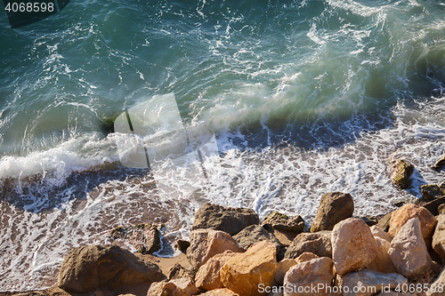 Image of Beautiful large yellow stones in green waves on sea coast