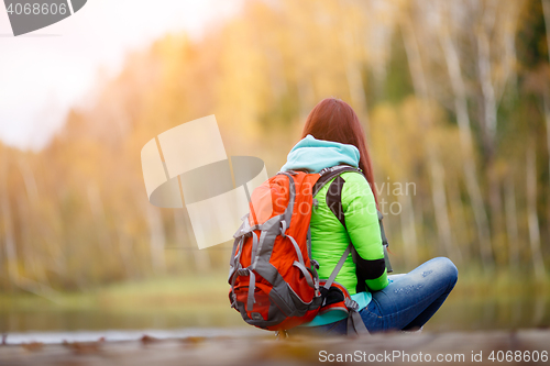 Image of Brunette sitting back on bridge in autumn