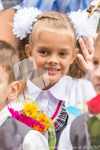 Image of First grader on the first of September, the line greeting waving friend