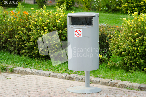 Image of Accurate cylindrical metal rubbish bin on a background of a well-kept lawn