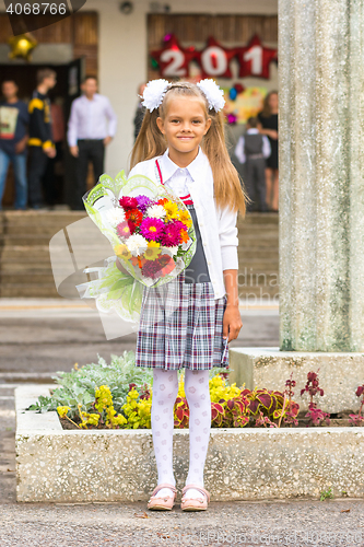 Image of Grower Baby girl first-grader with a bouquet of flowers at the school