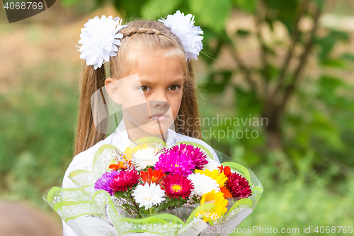 Image of Portrait of a seven-year schoolgirl with a big bouquet in hands