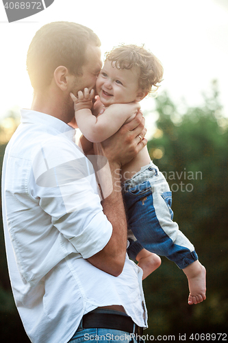 Image of Young beautiful father and little toddler son against green grass