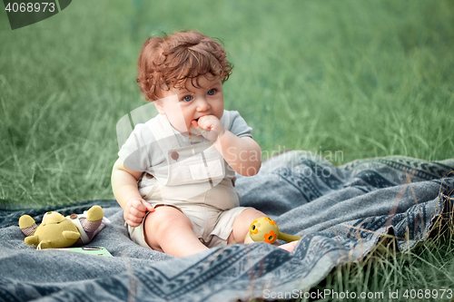 Image of The little baby or year-old child on the grass in sunny summer day.