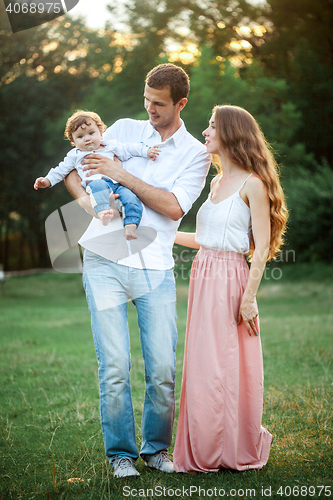 Image of Young beautiful father, mother and little toddler son against green trees