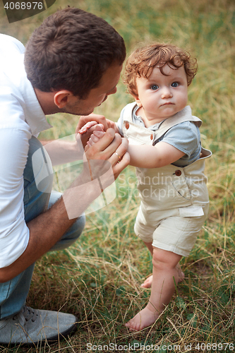 Image of Young beautiful father and little toddler son against green grass