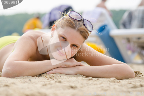 Image of Young girl lying on sandy beach and smiling looks into the frame