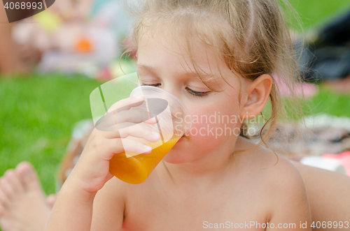 Image of Girl drinking fruit juice from a plastic disposable cup