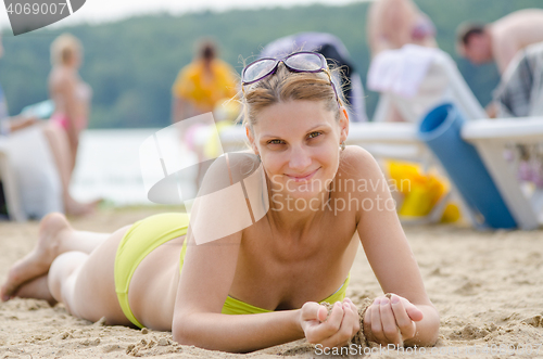 Image of A young girl picked up sand lying on his stomach on the sandy beach