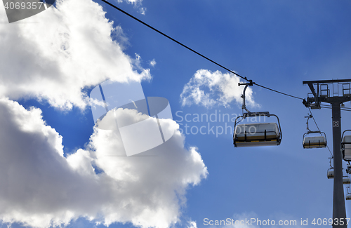 Image of Chair-lift and blue sky with sunlight clouds