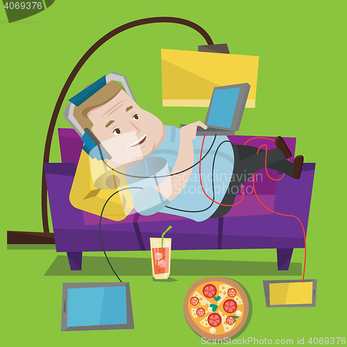 Image of Man lying on sofa with many gadgets.