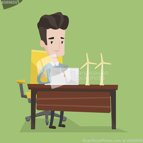 Image of Man working with model wind turbines on the table.