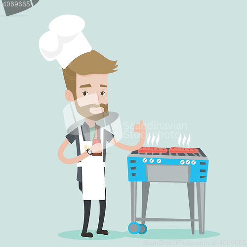 Image of Man cooking meat on gas barbecue grill.