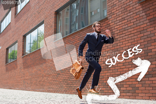 Image of young businessman running in a city street