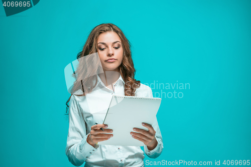 Image of The thoughtful young business woman with pen and tablet for notes on blue background