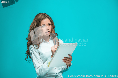 Image of The thoughtful young business woman with pen and tablet for notes on blue background