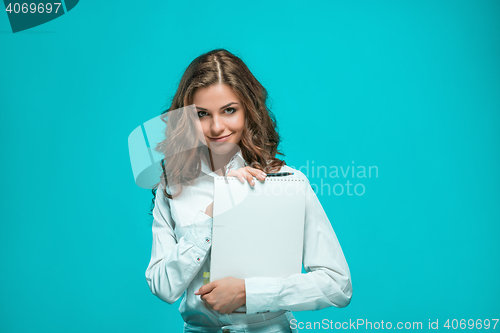 Image of The smiling young business woman with pen and tablet for notes on blue background