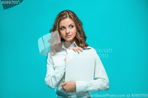 Image of The smiling young business woman with pen and tablet for notes on blue background