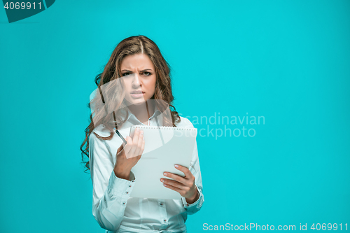 Image of The thoughtful young business woman with pen and tablet for notes on blue background