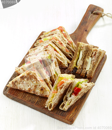 Image of various triangle sandwiches on wooden board