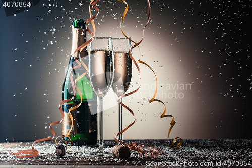 Image of Glasses of champagne, green bottle and snow flakes