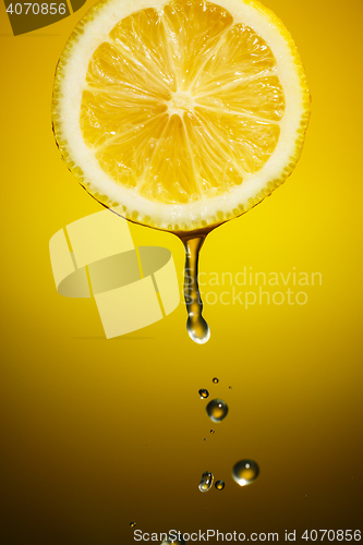 Image of Lemon slice and drops of juice on orange background
